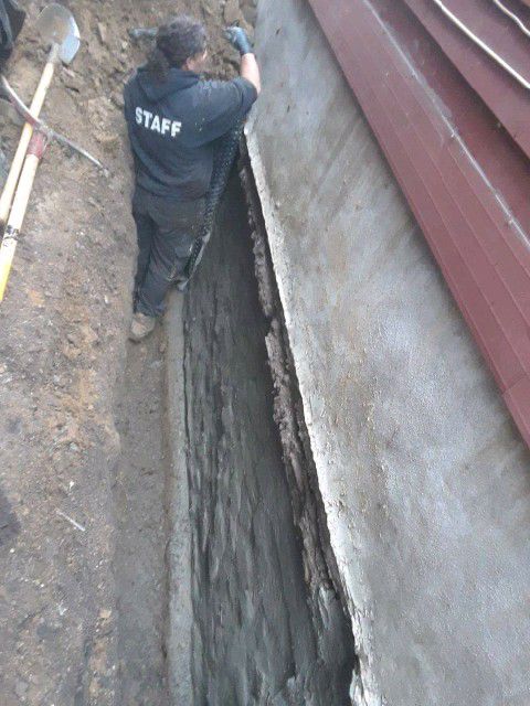 Staff performing basement wall repair for waterproofing a house